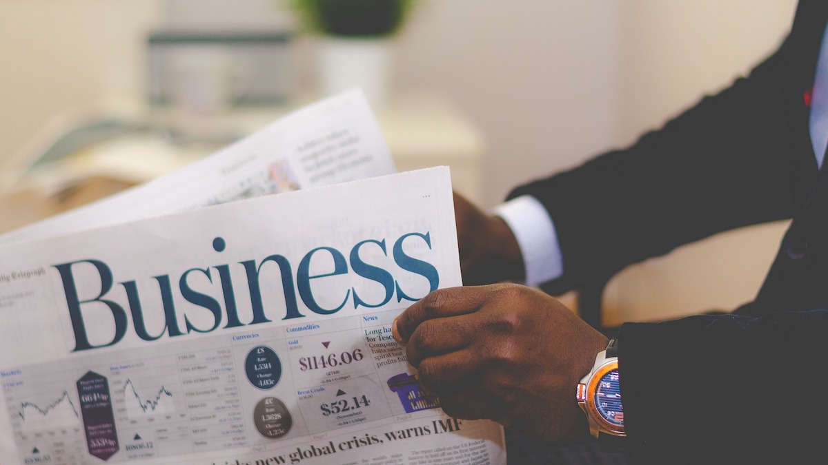 Man holding business section of a newspaper