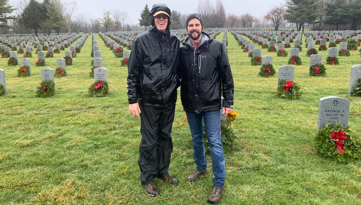 Kevin Murphy and his dad standing in front of a cemetery with freshly laid wreaths