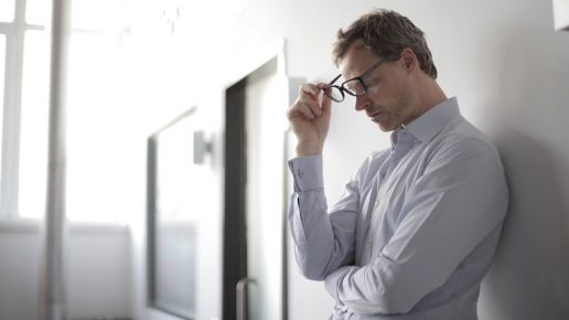 Businessman taking off glasses in frustration