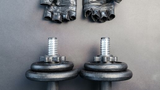 Weights and weight lifting gloves on a gym floor surface